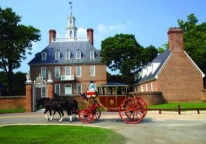 Man dressed in colonial clothes driving a horse and buggy in front of the Governor's Palace in Williamsburg, VA