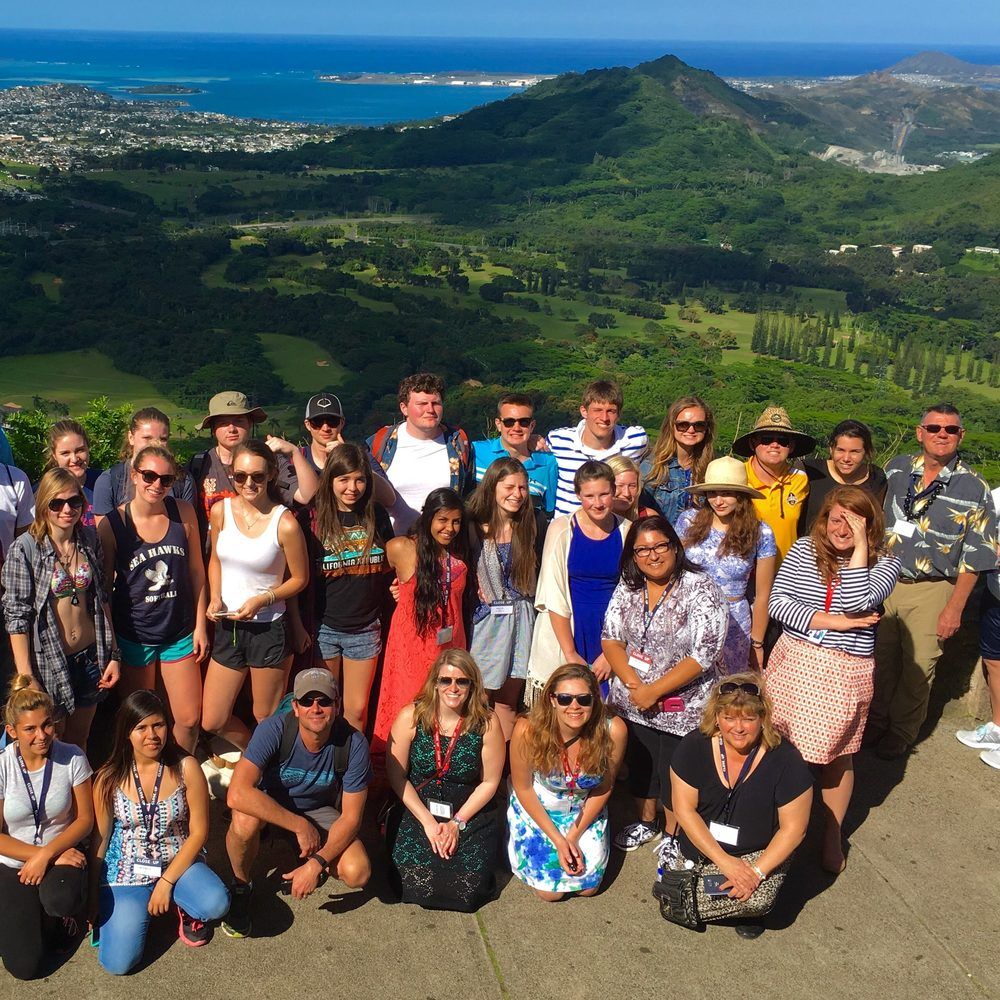 Group of high school students posing on a mountain top with beautiful views in Hawaii