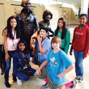 Middle school students posing with a statue of George Washington at Mount Vernon