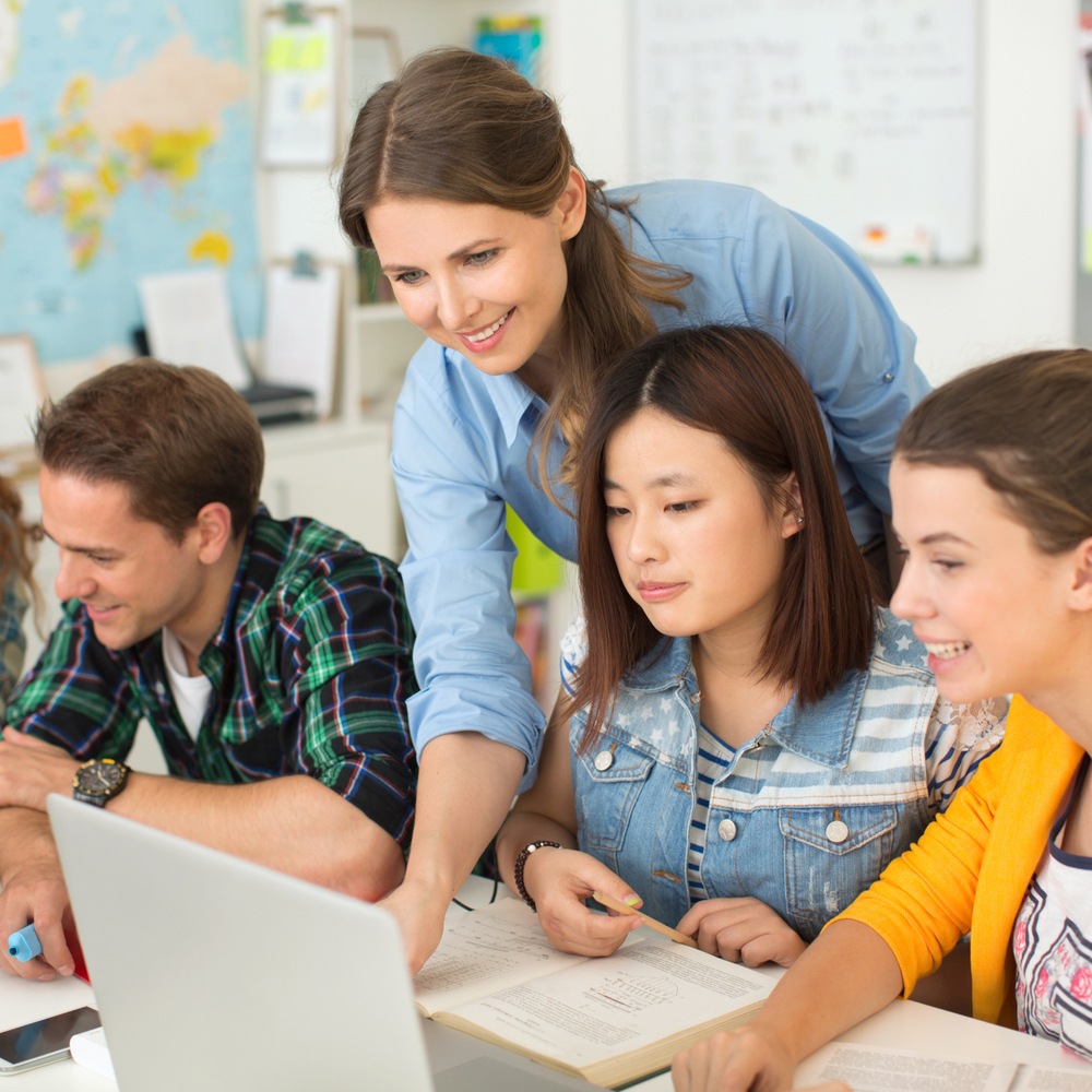 Teacher helps student with work on computer